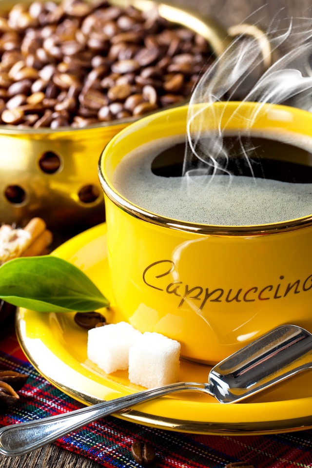 Желтая чашка с горячим кофе на столе с зернами и корицей 