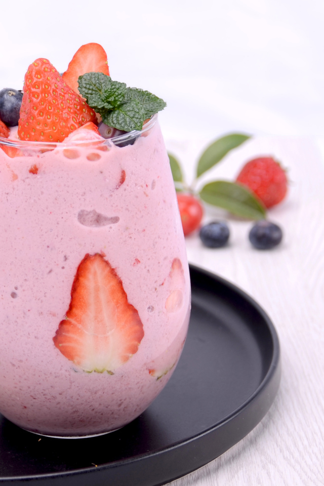 Йогурт в стакане с ягодами черники и клубники