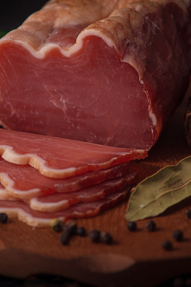 Кусок вяленого мяса на доске с черным хлебом и специями