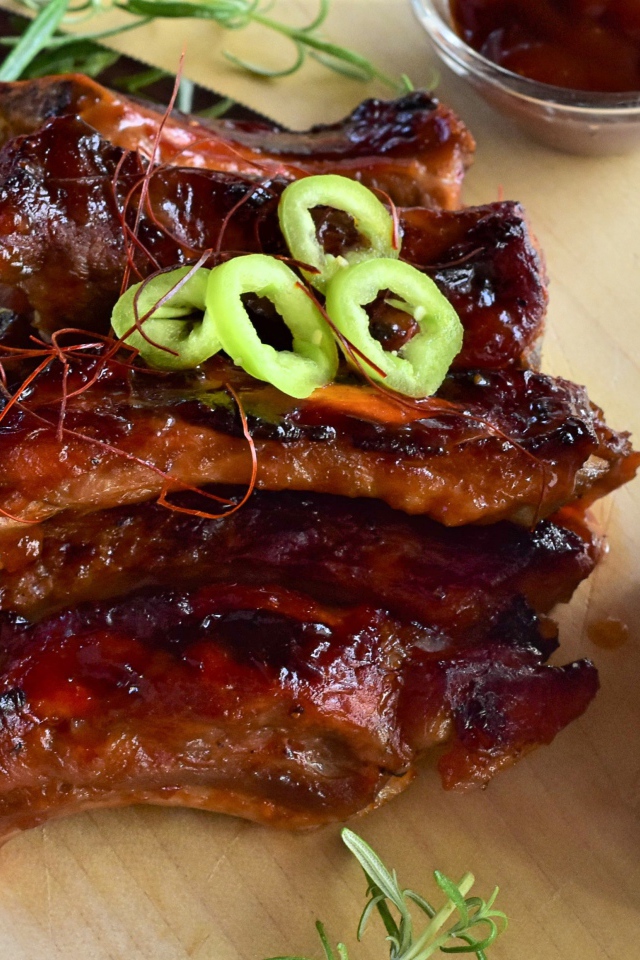 Аппетитные жареные ребрышки на столе с огурцами  и соусом 