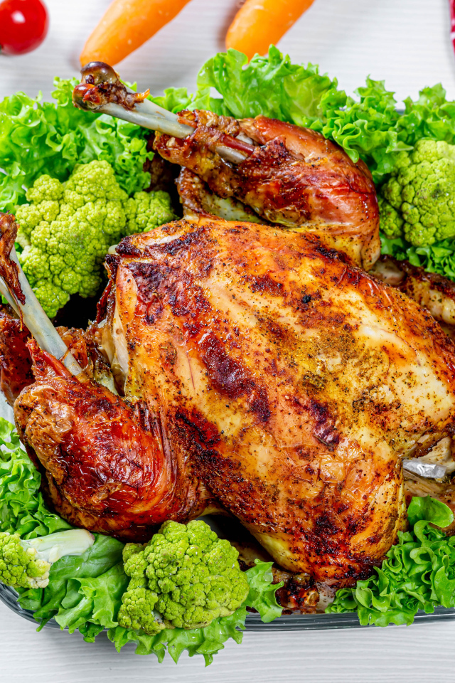 Запеченная курица с брокколи и листьями салата на столе с овощами