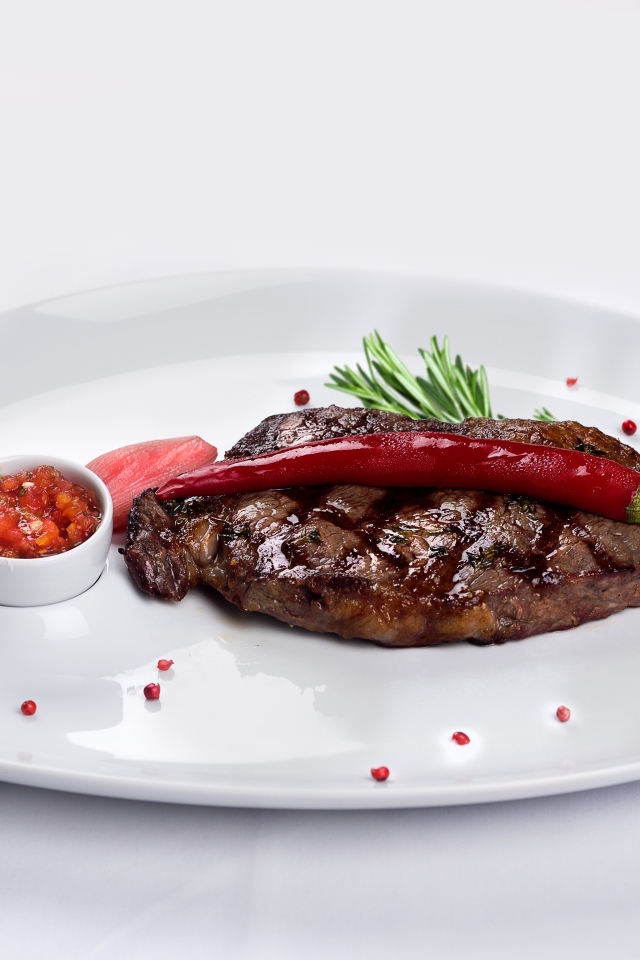 Стейк с кровью на тарелке с красным перцем