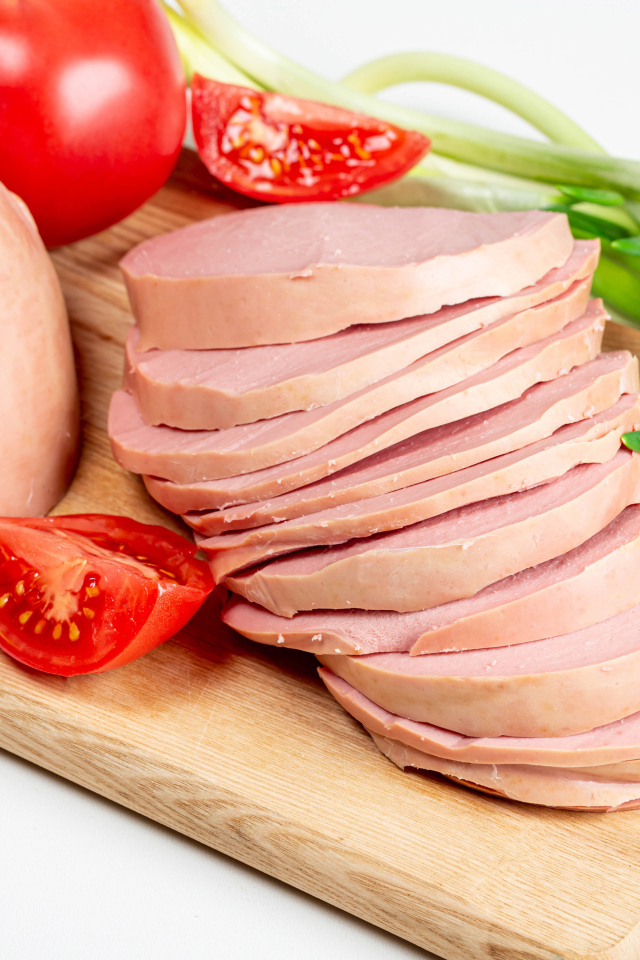 Вареная колбаса на доске с луком и помидором