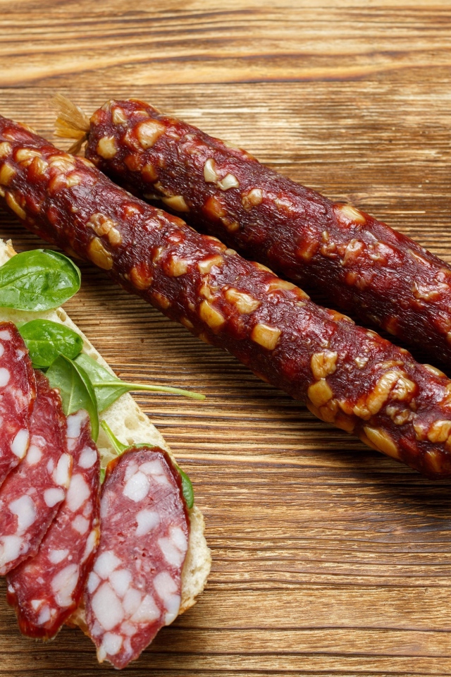 Вкусная сухая колбаса на столе с бутербродом