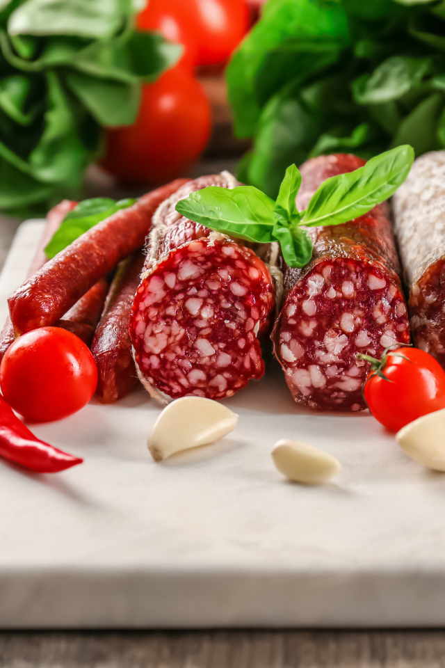 Вкусные колбасные изделия на столе с овощами