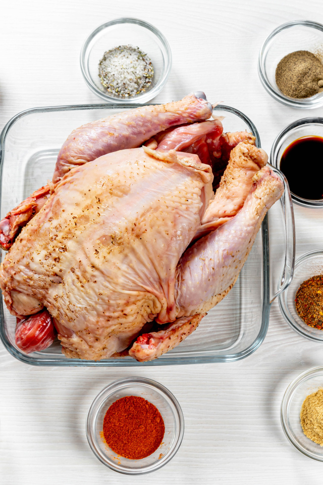 Свежая курица на противне на столе со специями 