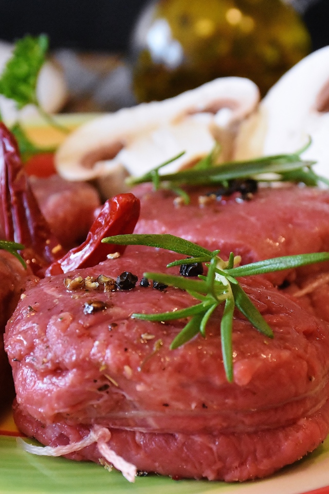 Свежее мясо маринуется со специями на столе с грибами