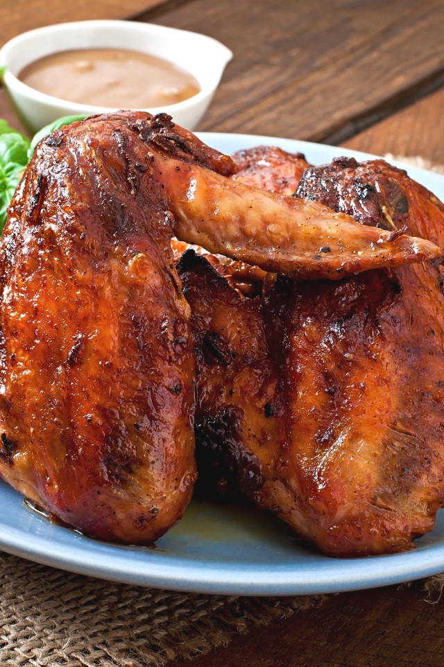 Зажареные куриные крылышки на столе с соусом и базиликом