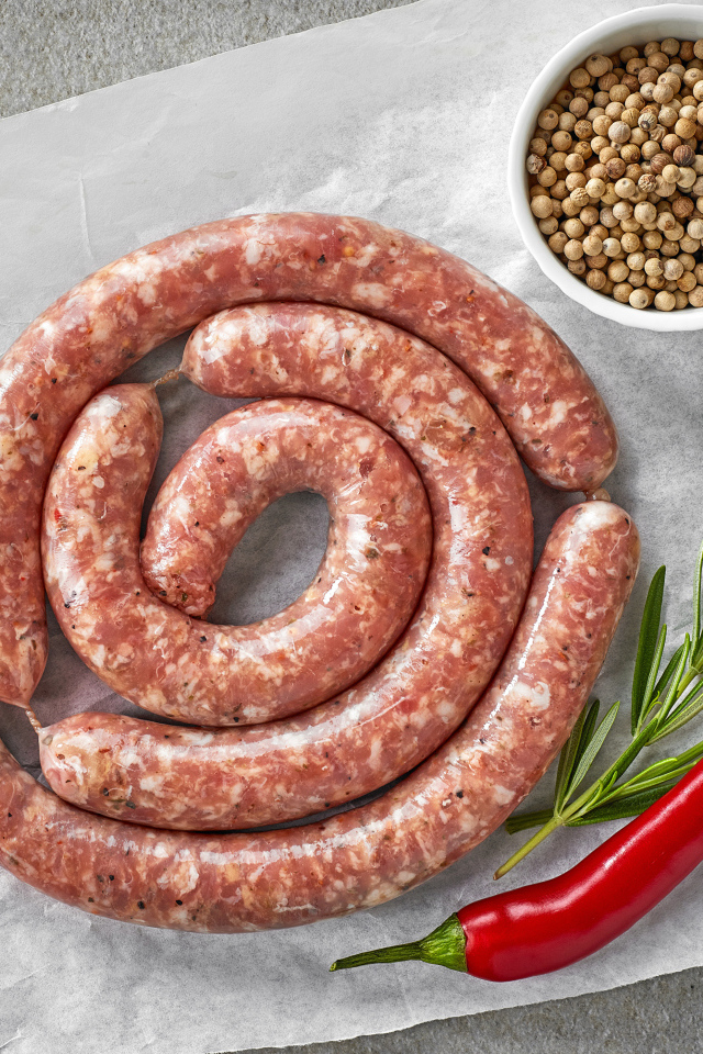 Домашняя колбаса на столе с зеленью и перцем