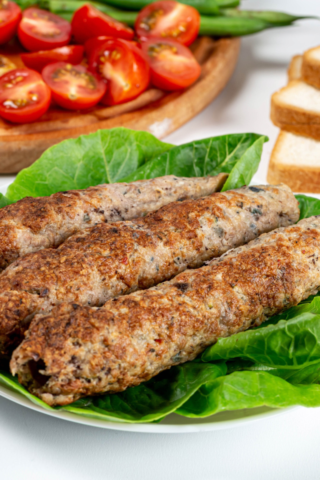Мясное блюдо кебаб на столе с зелеными листьями 