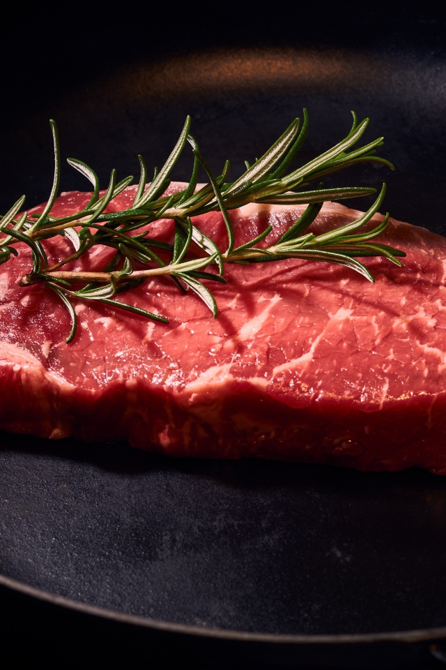 Кусок мяса на сковороде с розмарином