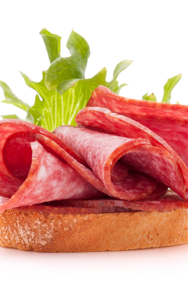 Бутерброд с листьями салата и колбасой на белом фоне
