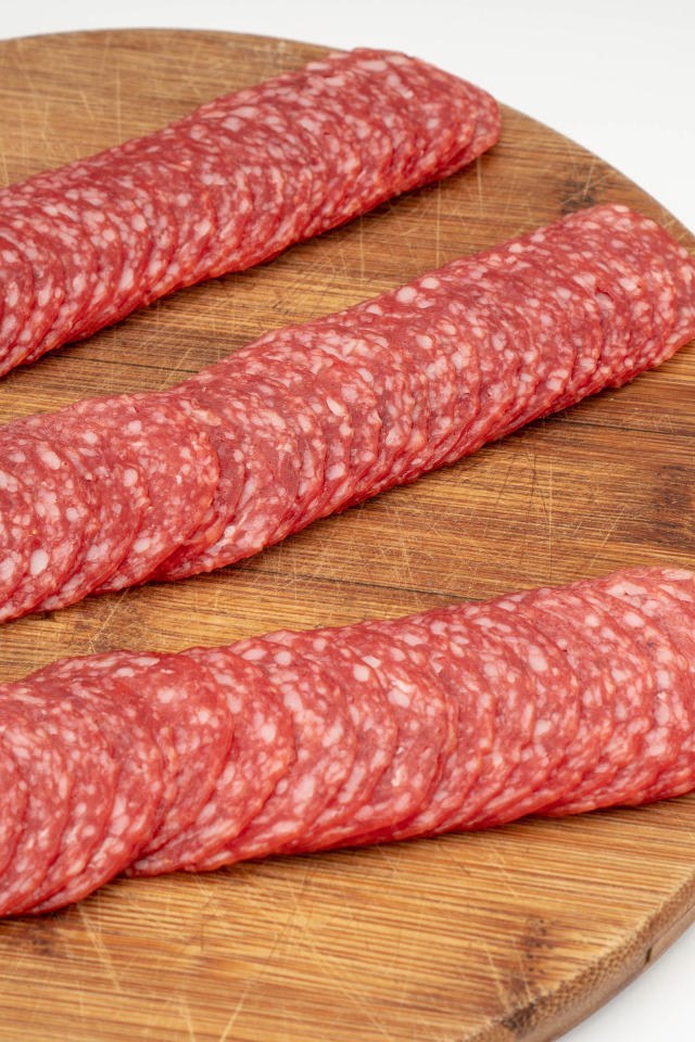 Колбаса тонко нарезана на разделочной доске 