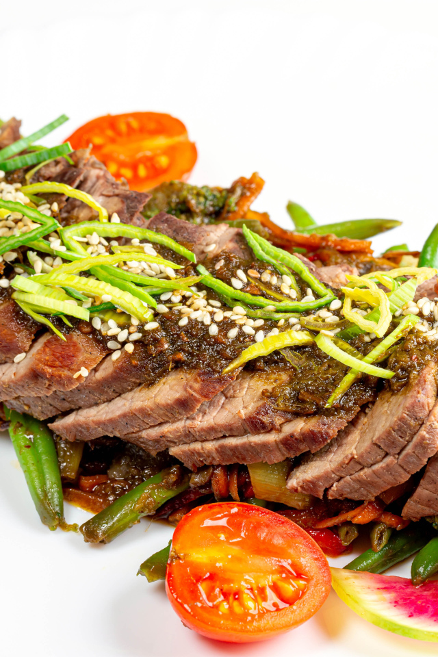 Мясо нарезанное кусочками на белом фоне с овощами