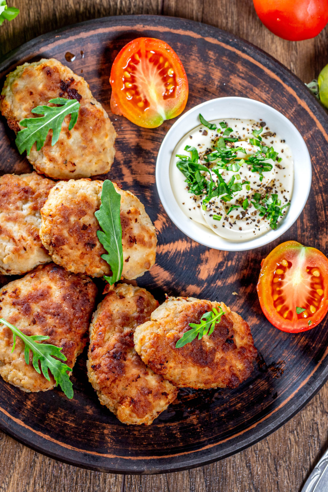 Вкусные котлеты на столе с соусом и помидорами