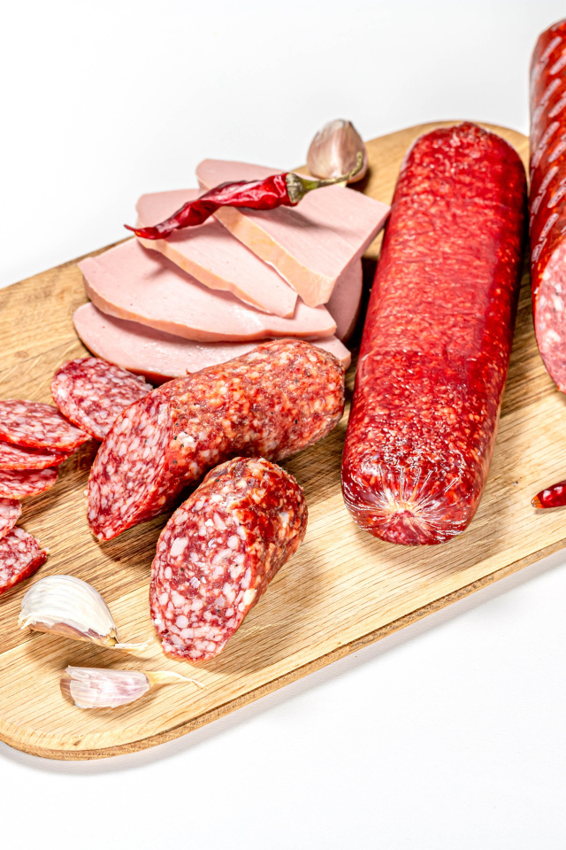 Вкусная колбаса с красным перцем и чесноком на доске на белом фоне