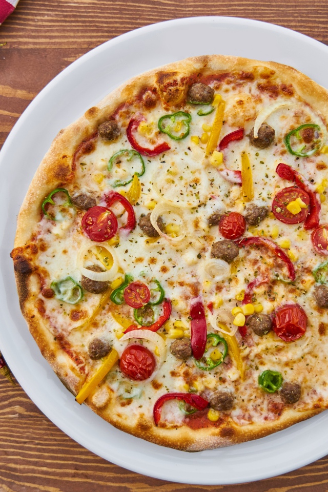 Аппетитная вкусная пицца на столе с овощами 