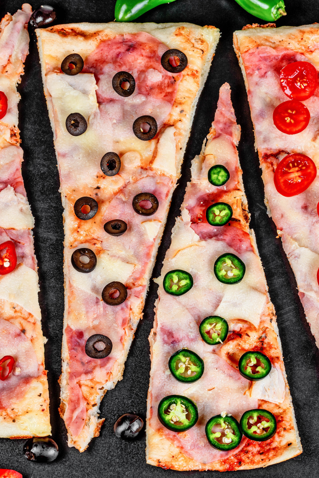 Четыре куска аппетитной пиццы с ветчиной и острым перцем