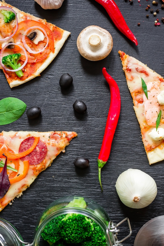 Куски пиццы на столе с овощами и соусом