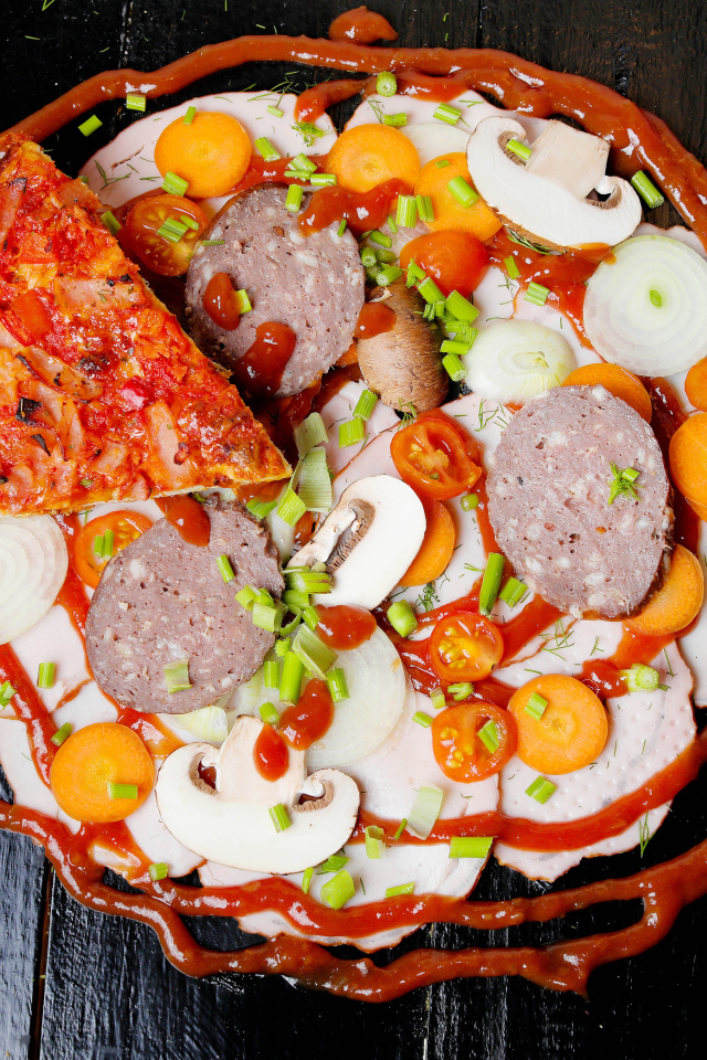 Pizza with vegetables and sausage on a table with ketchup