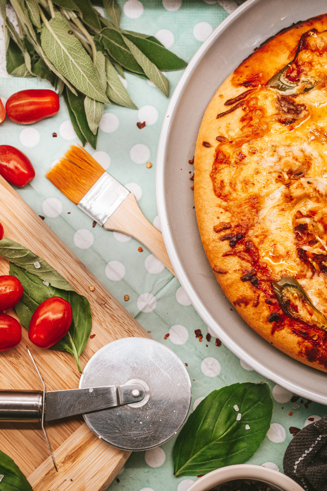 Румяная пицца на столе с сыром и помидорами