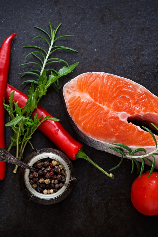 Кусок свежей красной рыбы на столе со специями, красным перцем и помидорами