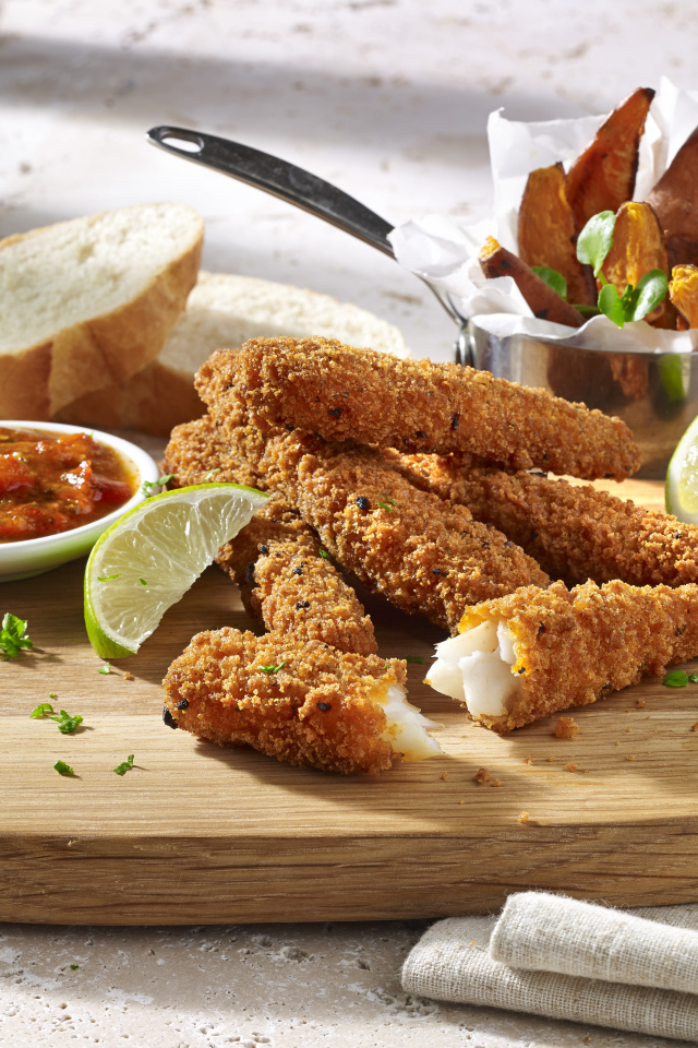 Рыба в панировке на столе с соусом и кусочками лайма