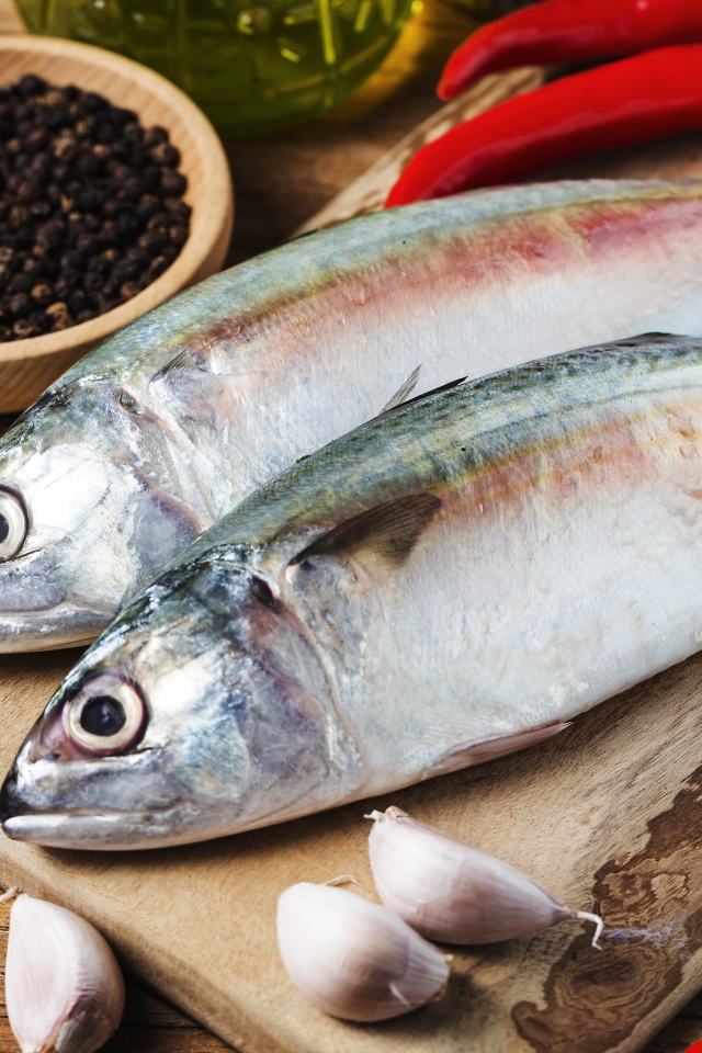 Свежая рыба лежит на доске с чесноком и специями