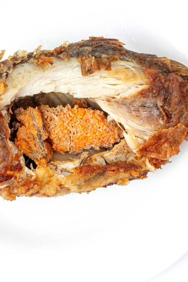 Жареная рыба с икрой внутри на белом фоне