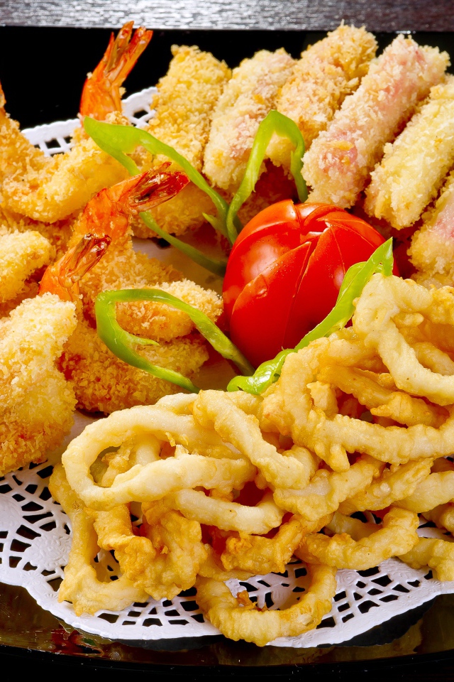 Морепродукты в кляре на тарелке с помидором