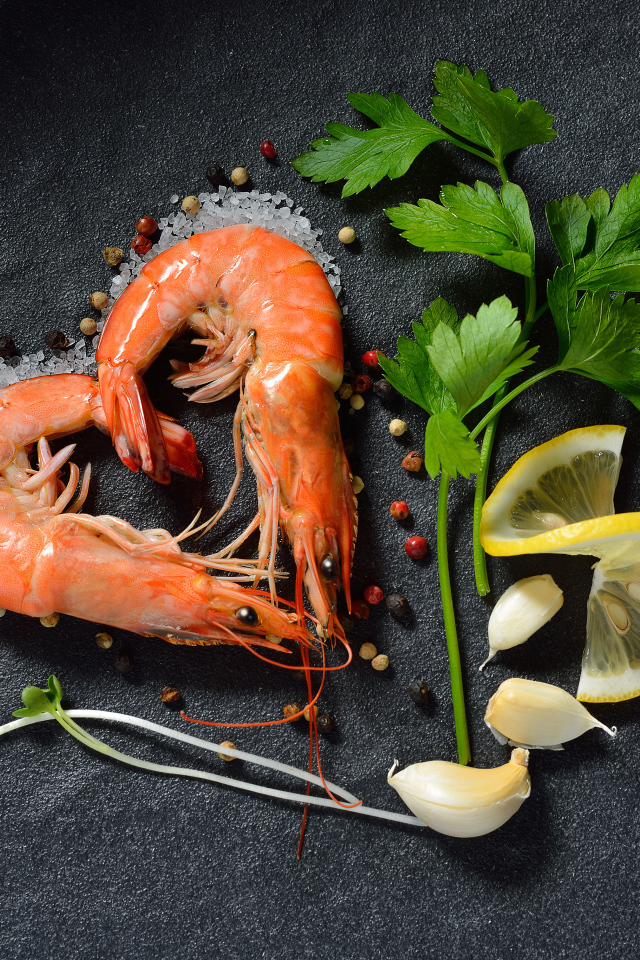 Сердце из креветок на сером столе с лимоном и веточкой петрушки 