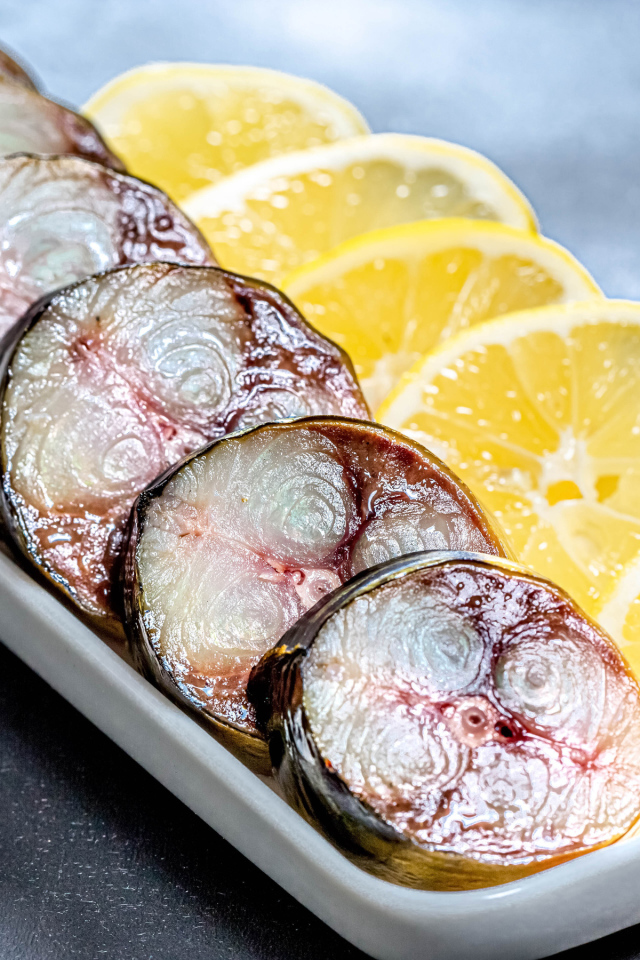 Куски скумбрии в тарелке с кусочками лимона 