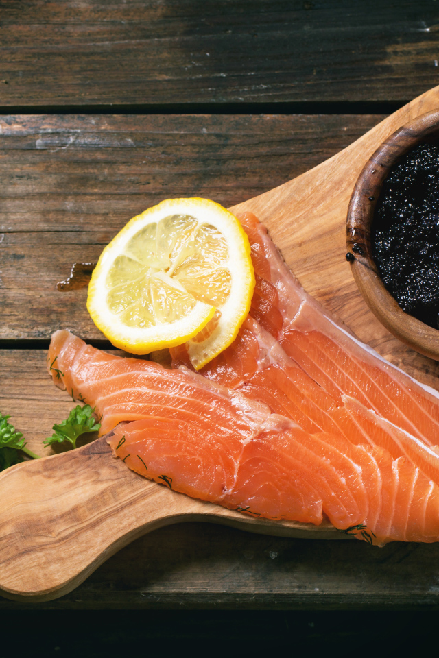 Кусочки красной рыбы с лимоном на столе с черной икрой 