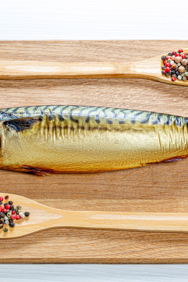 Копченая скумбрия на разделочной доске с перцем на белом фоне