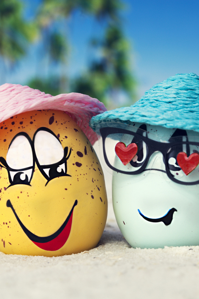 Два яйца в шляпах на песке с морскими звездами летом