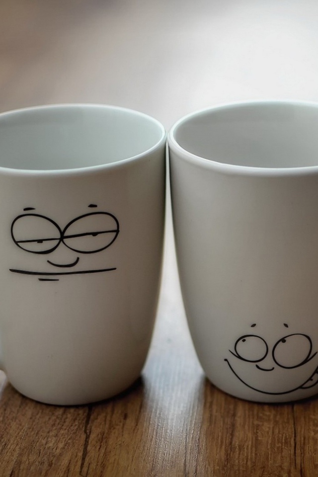 Две белые кружки с рисунками на столе 