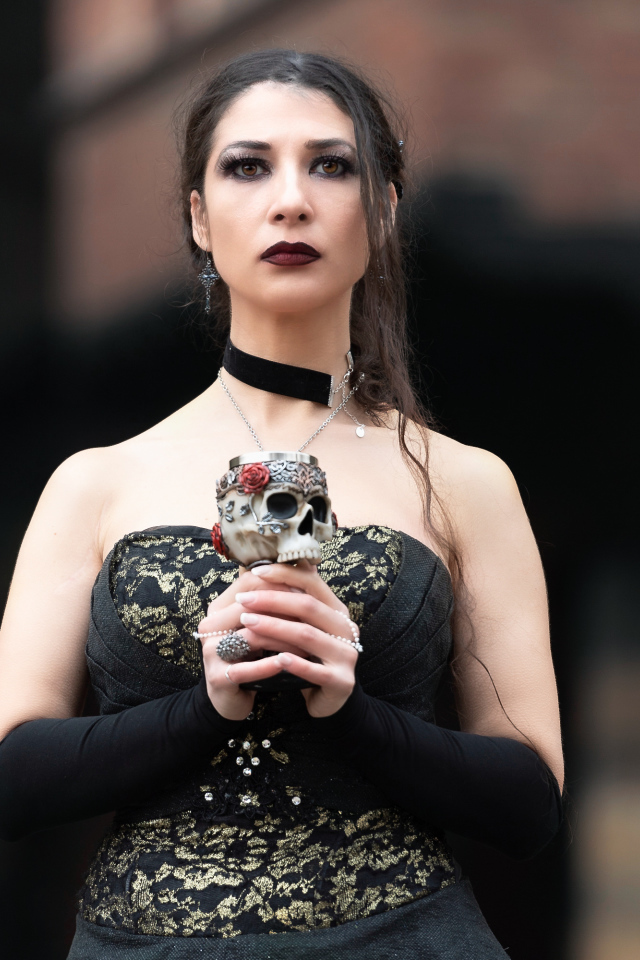 Девушка готка с бокалом - черепом в руках 