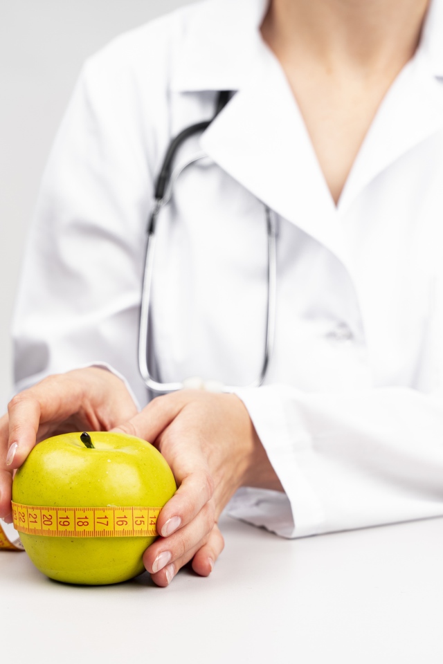 Woman doctor measures an apple with a centimeter