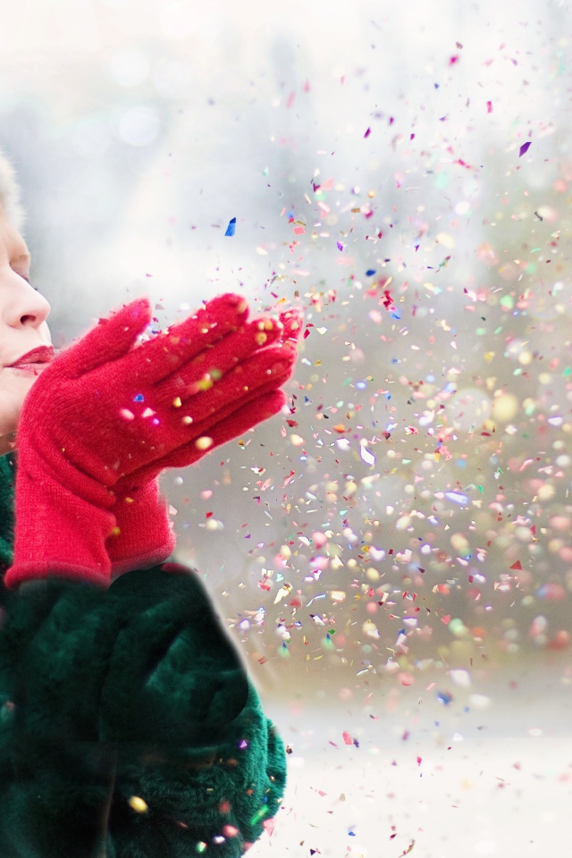 Женщина в шубе сдувает конфетти с ладоней