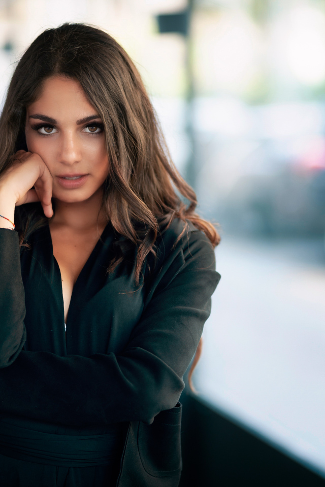 Милая девушка в черном наряде стоит на остановке