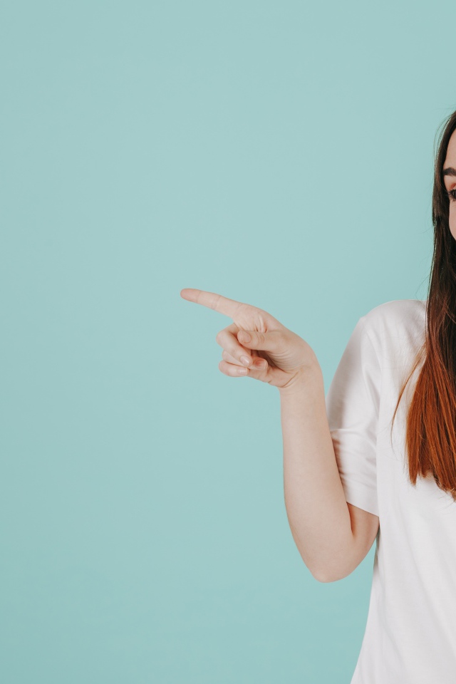 Девушка в белой футболке показывает на кого то пальцем