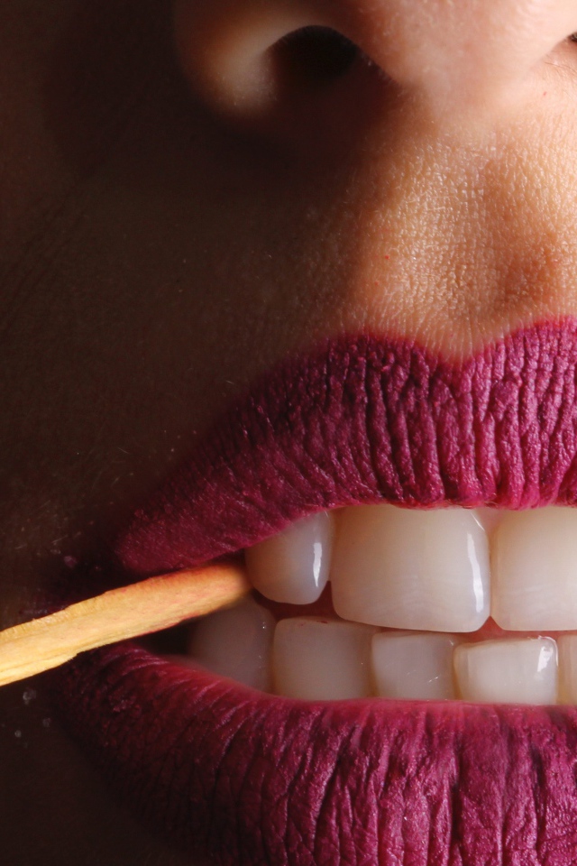 Зажженная спичка в зубах у девушки 