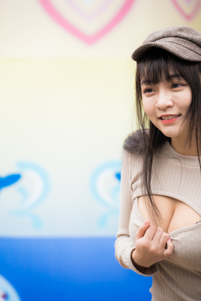 Улыбающаяся девушка азиатка стоит у стены  с рисунком