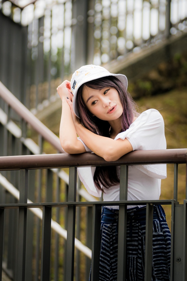 Молодая девушка азиатка стоит на лестнице у перил 