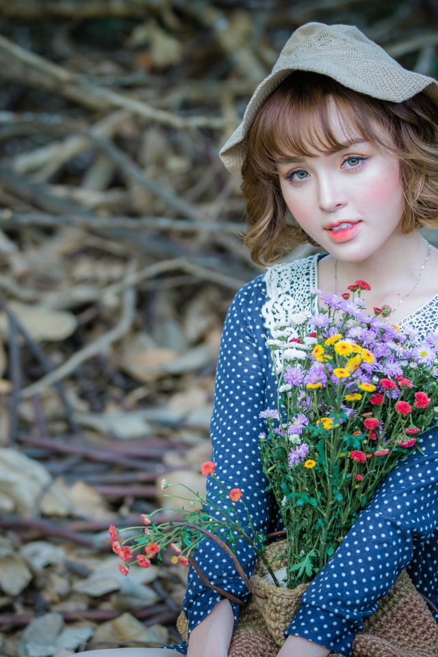 Молодая девушка азиатка с букетом цветов сидит на ветках