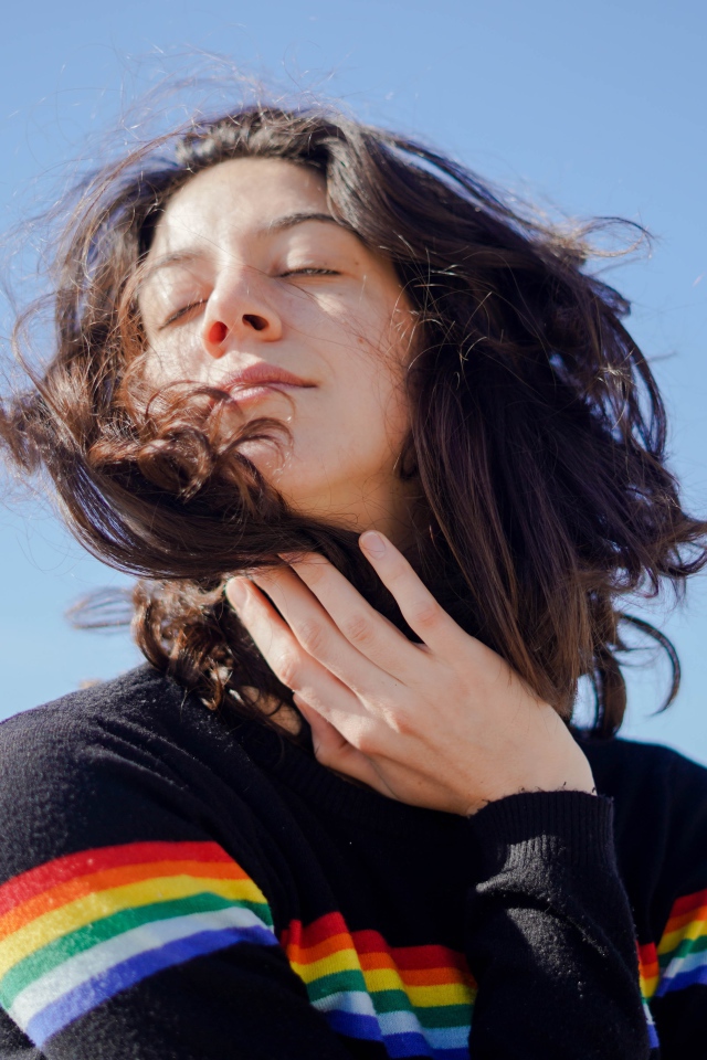 Молодая девушка греет лицо на солнце