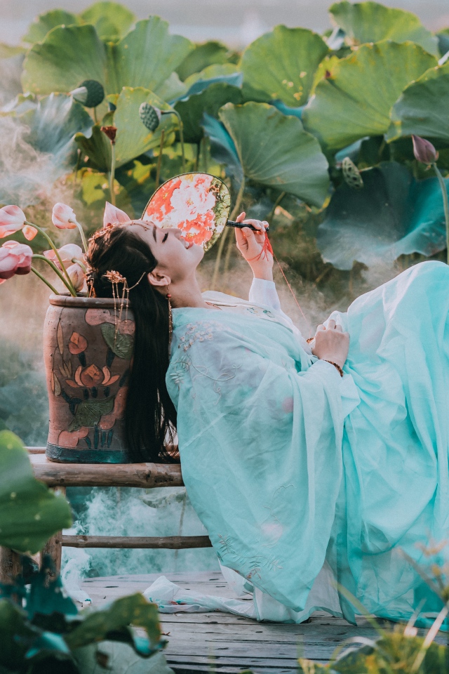 Девушка азиатка в красивом голубом платье на поле лотосов