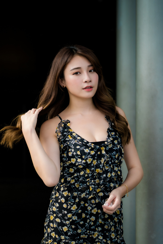 Девушка азиатка в платье трогает волосы 