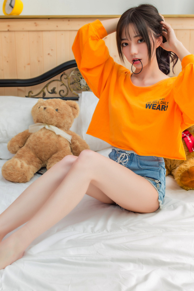 Девушка азиатка на кровати с игрушками