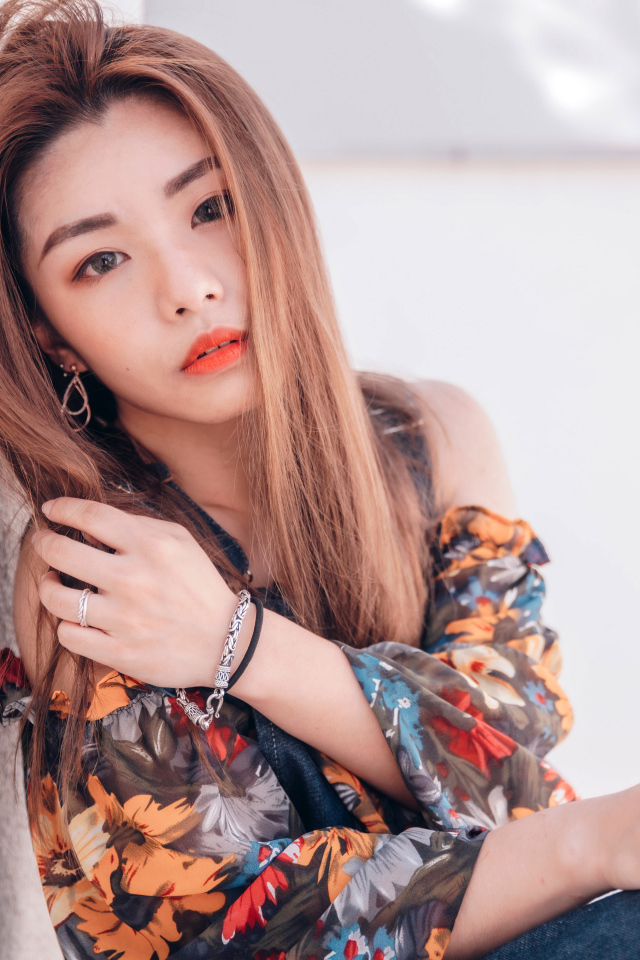 Девушка азиатка сидит на полу у стены 